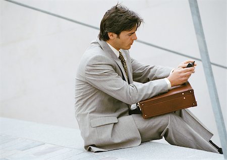 simsearch:695-03381608,k - Businessman sitting on stairs, looking at cell phone Foto de stock - Sin royalties Premium, Código: 695-03381629