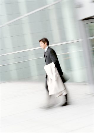 simsearch:695-03386819,k - Businessman walking, holding overcoat, blurred Foto de stock - Sin royalties Premium, Código: 695-03381651