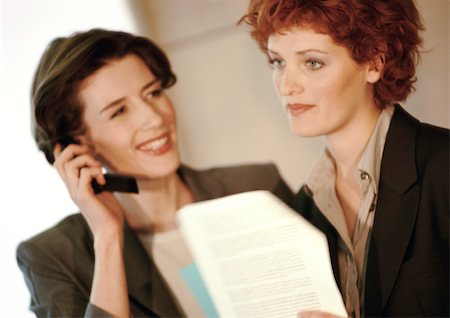 Two businesswomen side by side, one using phone Stock Photo - Premium Royalty-Free, Code: 695-03381736