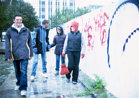 simsearch:632-01137036,k - Four young people walking on sidewalk next to graffiti-covered wall Foto de stock - Sin royalties Premium, Código: 695-03382247