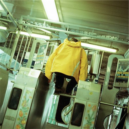 Young man jumping over turnstile in subway Fotografie stock - Premium Royalty-Free, Codice: 695-03382569
