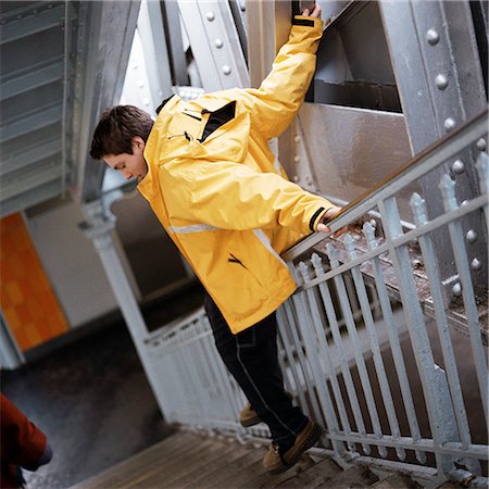 simsearch:700-03017820,k - Teenage boy in raincoat sliding down handrail in stairway Foto de stock - Sin royalties Premium, Código: 695-03382577