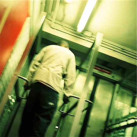 simsearch:695-03382568,k - Young man standing in front of subway exit door, rear view, low angle view Fotografie stock - Premium Royalty-Free, Codice: 695-03382578