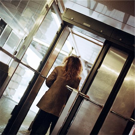 simsearch:695-03382580,k - Young woman walking through subway station doorway, view from rear. Fotografie stock - Premium Royalty-Free, Codice: 695-03382572