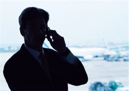 shadow silhouette man - Man wearing suit, holding cell phone to ear, silhouette, airplanes in background Stock Photo - Premium Royalty-Free, Code: 695-03382793