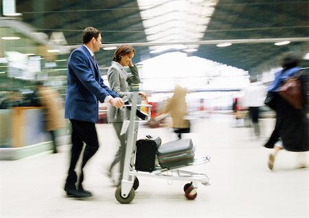 suitcase walking away - Businessman and businesswoman walking together with luggage through station, blurred. Stock Photo - Premium Royalty-Free, Code: 695-03382943