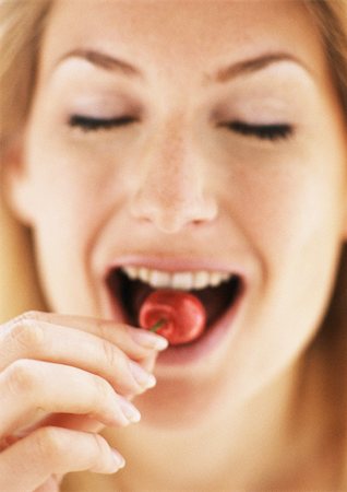 simsearch:695-03375576,k - Woman eating a cherry, focus on fingers in foreground, close-up Foto de stock - Sin royalties Premium, Código: 695-03383573