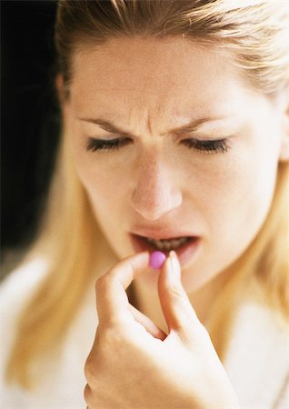 Woman putting pill in mouth, close-up Stock Photo - Premium Royalty-Free, Code: 695-03383612