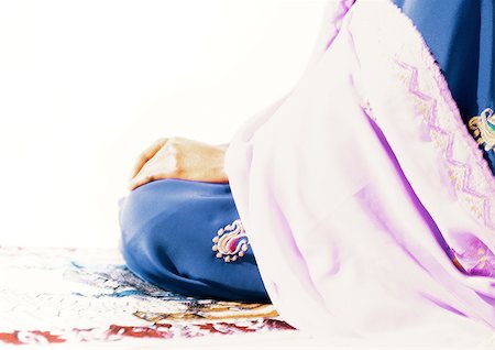 Muslim woman sitting on prayer rug Stock Photo - Premium Royalty-Free, Code: 695-03383639