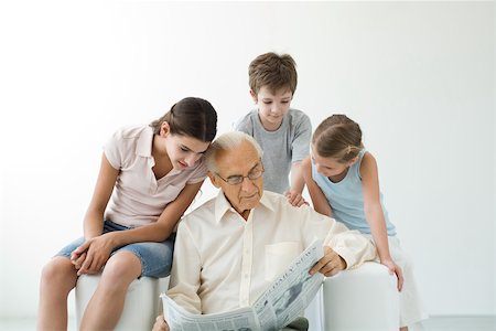 four generation of men in a photo - Grandfather reading newspaper, three grandchildren looking over his shoulder Stock Photo - Premium Royalty-Free, Code: 695-03390004