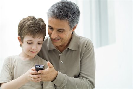 Mature man and young son looking at cell phone together Stock Photo - Premium Royalty-Free, Code: 695-03390013