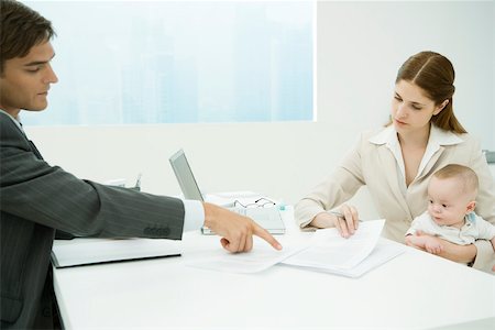 Professional woman in office, holding baby on lap, discussing documents with male colleague Stock Photo - Premium Royalty-Free, Code: 695-03390027