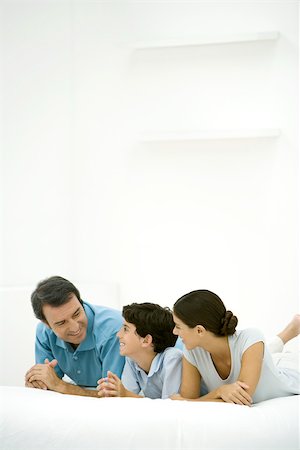 Family lying on bed together, smiling at each other Stock Photo - Premium Royalty-Free, Code: 695-03390052