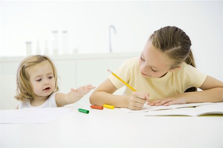 simsearch:695-03380035,k - Girl doing homework at table, younger sister reaching for crayons Foto de stock - Royalty Free Premium, Número: 695-03390098