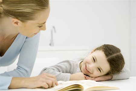 simsearch:695-03377942,k - Mother and daughter looking at book together, girl resting head on arms Foto de stock - Royalty Free Premium, Número: 695-03390110