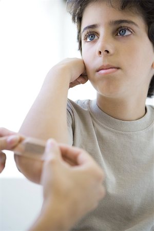 simsearch:649-07280892,k - Boy having adhesive bandage applied to his elbow, cropped view Fotografie stock - Premium Royalty-Free, Codice: 695-03390122