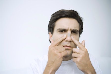 Man applying adhesive bandage on his nose, looking at camera Foto de stock - Royalty Free Premium, Número: 695-03390135