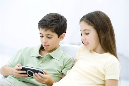 simsearch:695-05767801,k - Brother and sister sitting together, boy playing handheld video game Fotografie stock - Premium Royalty-Free, Codice: 695-03390257