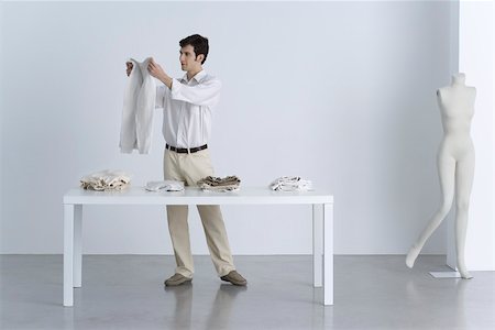 folding - Man standing beside table, holding up sweater Stock Photo - Premium Royalty-Free, Code: 695-03390288