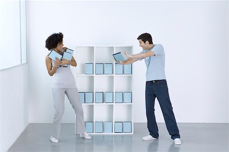 play fight - Man and woman joking, fighting over DVDs on shelf Stock Photo - Premium Royalty-Free, Code: 695-03390280