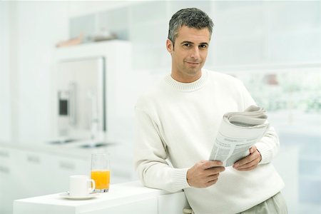 Man leaning against kitchen counter, holding newspaper, smiling at camera Foto de stock - Sin royalties Premium, Código: 695-03390307
