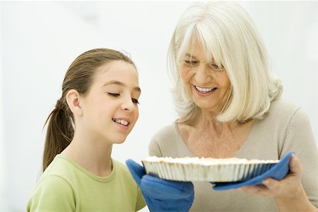 smelling food children - Grandmother and granddaughter looking down at freshly baked pie Stock Photo - Premium Royalty-Free, Code: 695-03390325