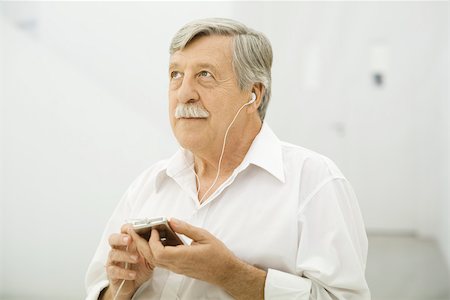 simsearch:693-06378948,k - Senior man listening to MP3 player, looking up Foto de stock - Royalty Free Premium, Número: 695-03390322