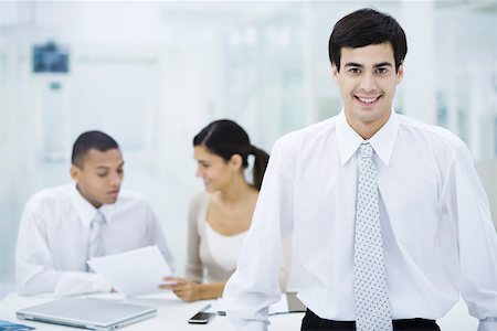 diverse leaders - Businessman smiling at camera, colleagues working in background Stock Photo - Premium Royalty-Free, Code: 695-03390357
