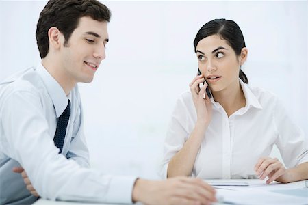 people shocked on phones - Colleagues sitting together at desk, woman using cell phone Stock Photo - Premium Royalty-Free, Code: 695-03390364