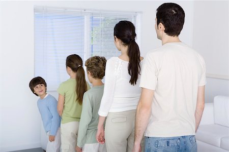 Family lined up shortest to tallest, youngest boy looking over shoulder at rest of family Foto de stock - Sin royalties Premium, Código: 695-03390385