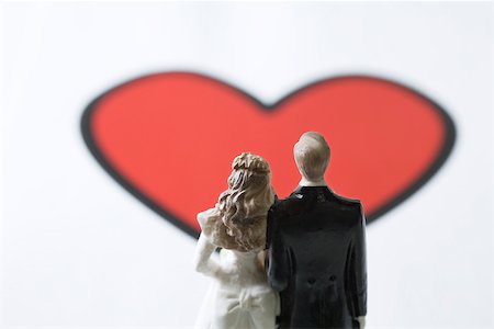 simsearch:633-02345827,k - Miniature bride and groom standing in front of large heart graphic Stock Photo - Premium Royalty-Free, Code: 695-03390462