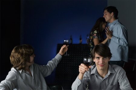 pic of friends in bar celebration - Men raising glasses, one looking over shoulder at dancing couple, other smiling at camera Foto de stock - Sin royalties Premium, Código: 695-03390487