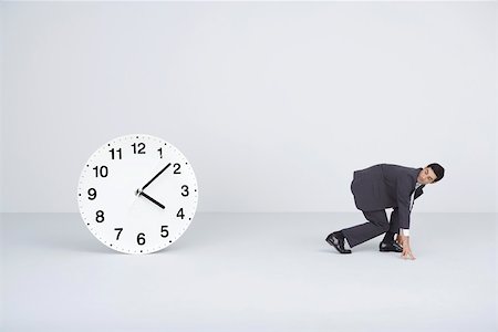 silhouette person running - Businessman racing against time, looking over shoulder at large clock Stock Photo - Premium Royalty-Free, Code: 695-03390550