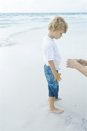 summer beach break - Boy standing on beach with parent Stock Photo - Premium Royalty-Free, Code: 696-03394017