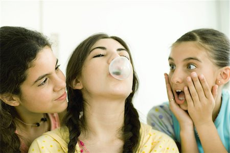 preteen girl surprise - Three young female friends, one blowing bubble while others watch Stock Photo - Premium Royalty-Free, Code: 696-03394100