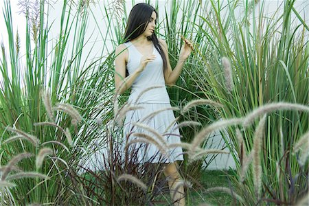 Woman standing in ornamental garden, looking at foliage Foto de stock - Sin royalties Premium, Código: 696-03394148