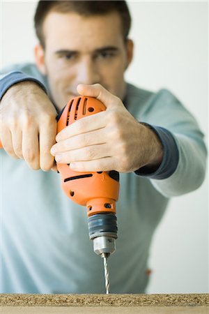 electric drill - Homme à l'aide de la perceuse, focus sur la perceuse au premier plan Photographie de stock - Premium Libres de Droits, Code: 696-03394179