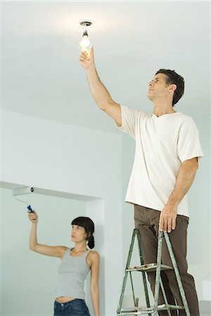 simsearch:695-03389240,k - Woman painting with paint roller, man changing light bulb Stock Photo - Premium Royalty-Free, Code: 696-03394186