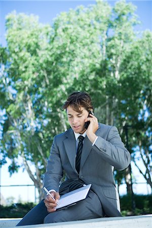 person on phone with clipboard - Young businessman sitting outdoors using laptop computer, writing Stock Photo - Premium Royalty-Free, Code: 696-03394335