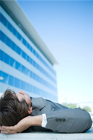 simsearch:696-03394943,k - Businessman lying on ground outdoors, hands behind head, cropped view Stock Photo - Premium Royalty-Free, Code: 696-03394336