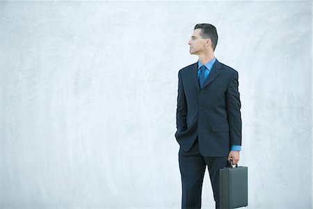 simsearch:695-03373745,k - Businessman standing, carrying briefcase, looking away Foto de stock - Royalty Free Premium, Número: 696-03394350