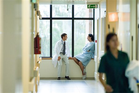 doctor patient friendly - Male doctor and patient sitting by window in hospital corridor, discussing, focus on background Stock Photo - Premium Royalty-Free, Code: 696-03394364