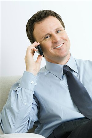 simsearch:633-01837165,k - Businessman using cell phone, smiling at camera, portrait Fotografie stock - Premium Royalty-Free, Codice: 696-03394636