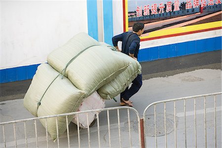 Man carting cushions through street, China, Guangdong Province, Guangzhou. Stock Photo - Premium Royalty-Free, Code: 696-03394894