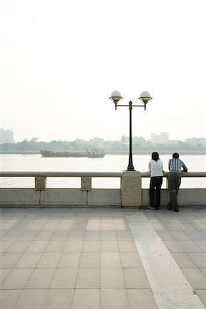 China, Guangdong Province, Guangzhou, couple looking at view over river, rear view Stock Photo - Premium Royalty-Free, Code: 696-03394909