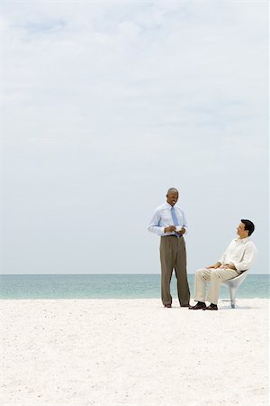 Two business associates chatting on beach, one holding coffee cup Stock Photo - Premium Royalty-Free, Code: 696-03395090
