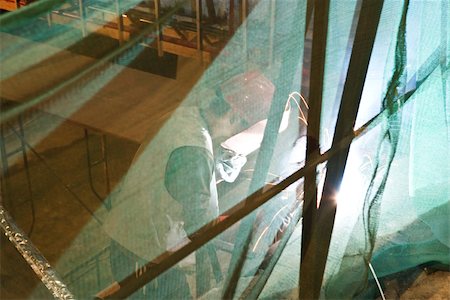 Construction worker behind safety net Stock Photo - Premium Royalty-Free, Code: 696-03395147