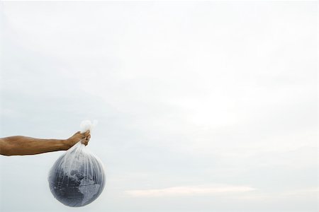 Man holding globe in plastic bag, cropped view Stock Photo - Premium Royalty-Free, Code: 696-03395213