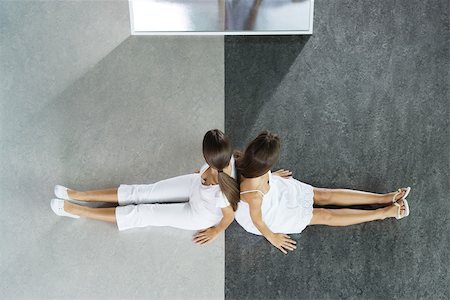 Two teenage girls sitting back to back on black and white divided floor, viewed from directly above Stock Photo - Premium Royalty-Free, Code: 696-03395278