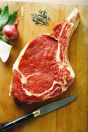 red meat - Raw steak on cutting board with herbs and knife, high angle view Stock Photo - Premium Royalty-Free, Code: 696-03395335